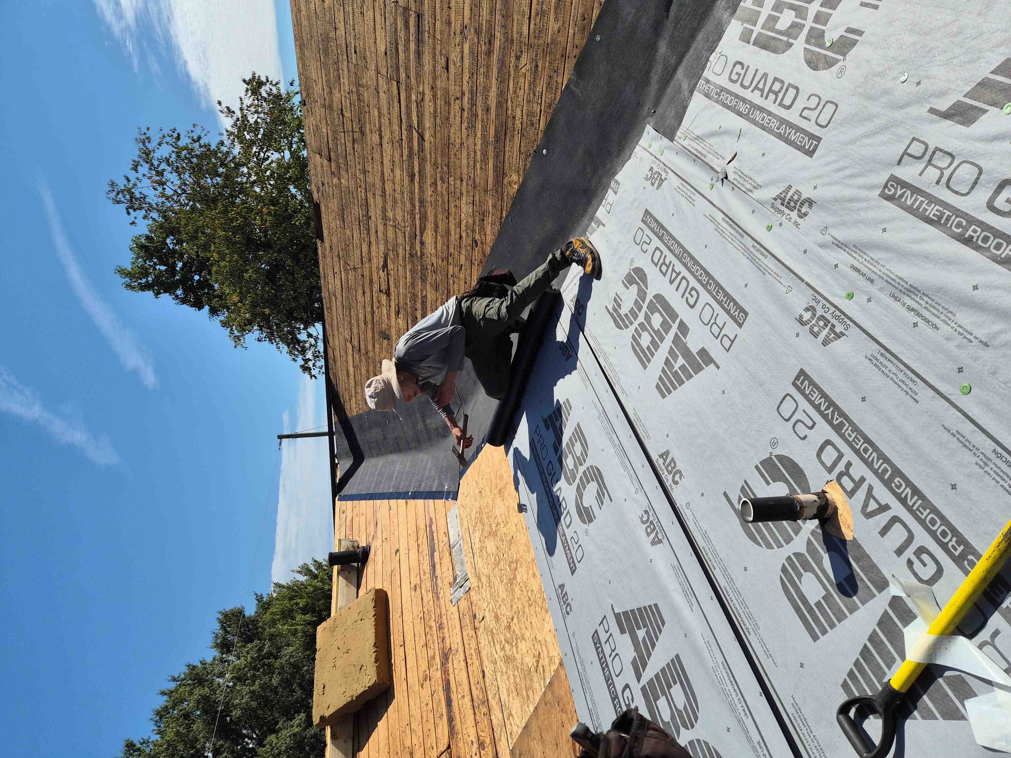 Installer hand-nailing synthetic underlayment to roof decking on a Winston-Salem NC job